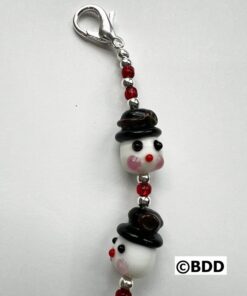A keychain with two faces and one has a hat on it.