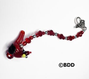 A red glass bird is hanging from the side of a chain.