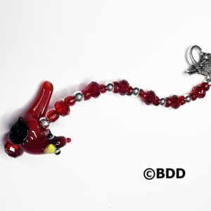 A red glass bird is hanging from the side of a chain.